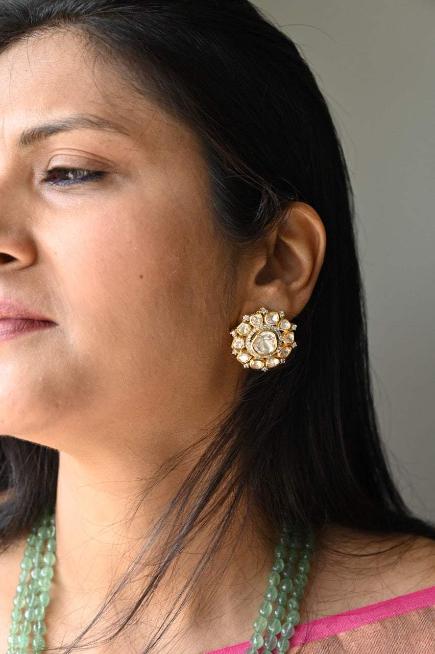 A person wearing a silver and green moissanite pendant mala with intricate designs and earrings.