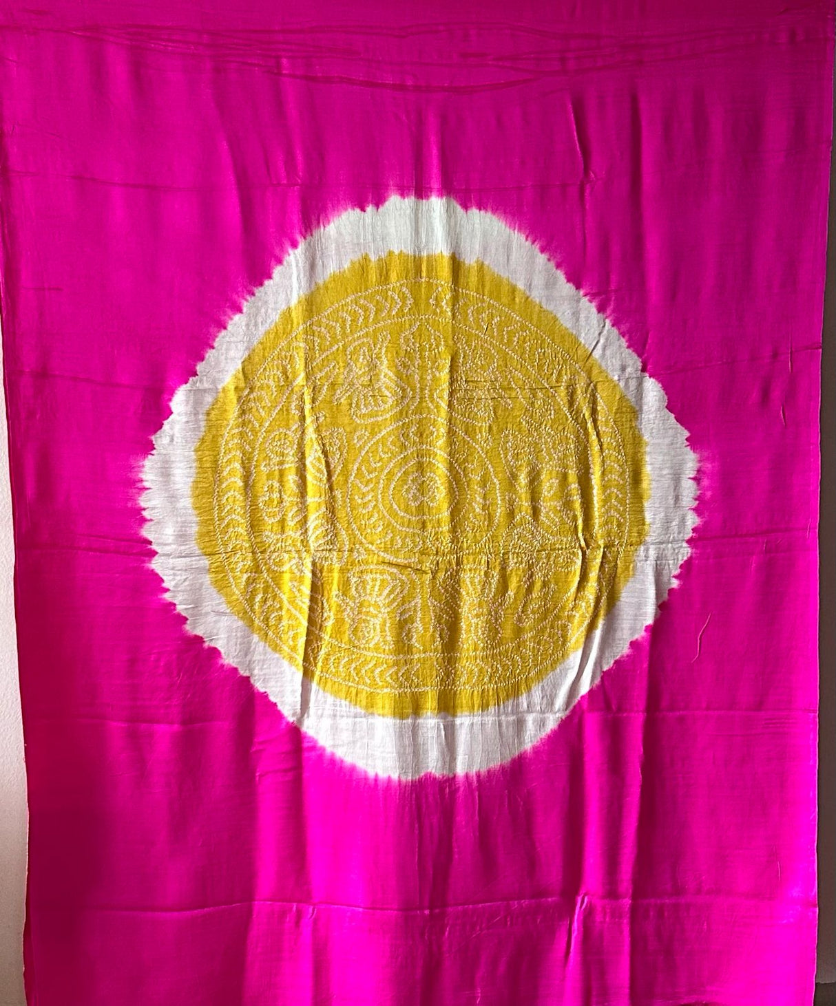 A pure Gajji silk pink and yellow bandhani saree draped and displayed, with intricate circle patterns.