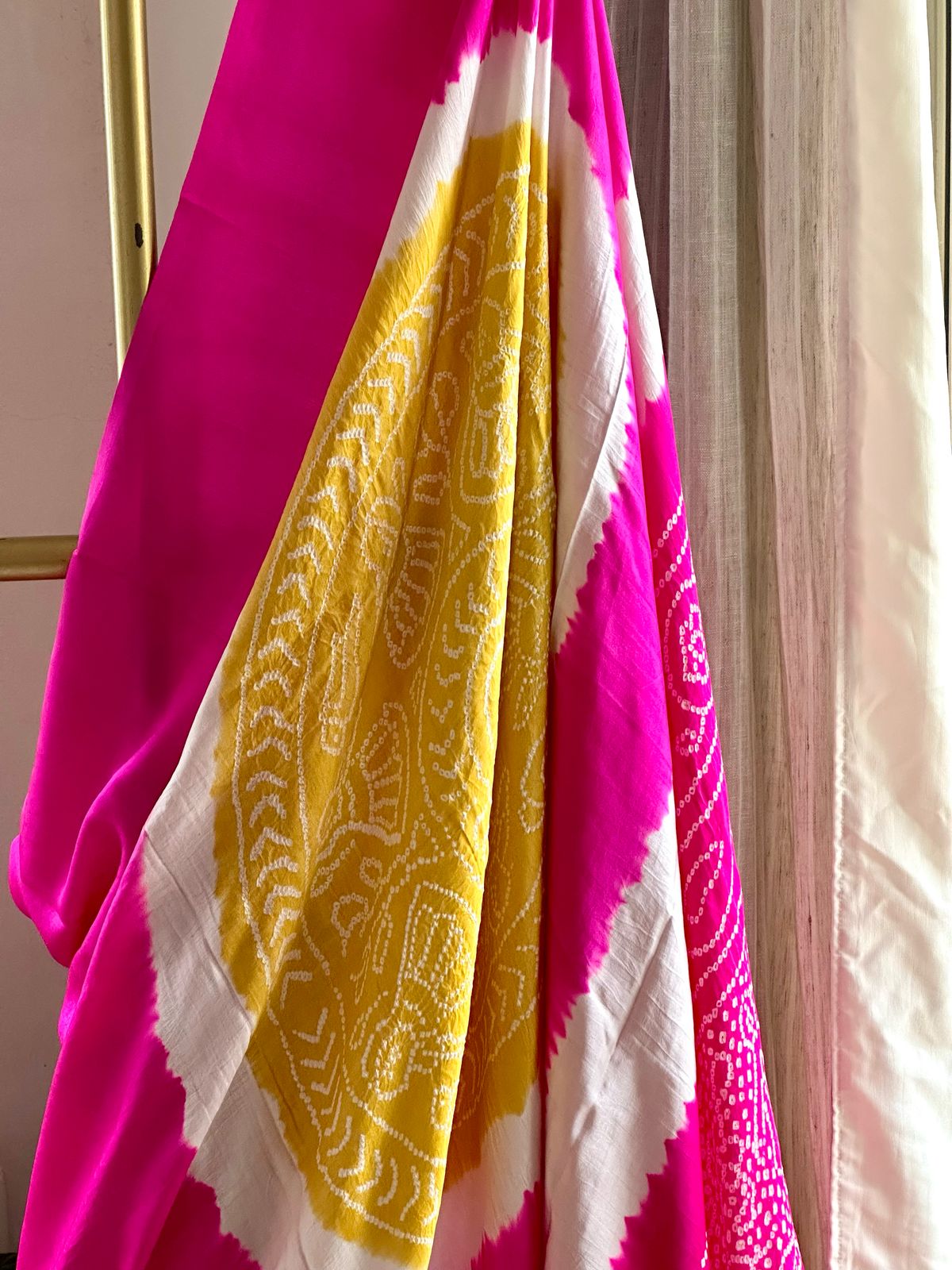A pure Gajji silk pink and yellow bandhani saree draped and displayed, with intricate circle patterns.