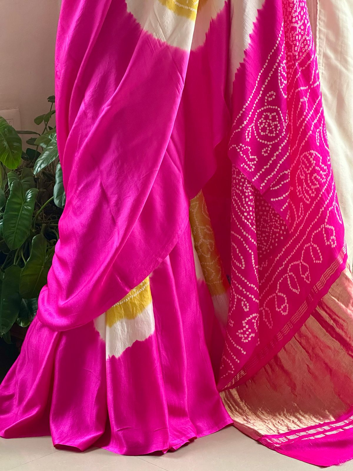 A pure Gajji silk pink and yellow bandhani saree draped and displayed, with intricate circle patterns.