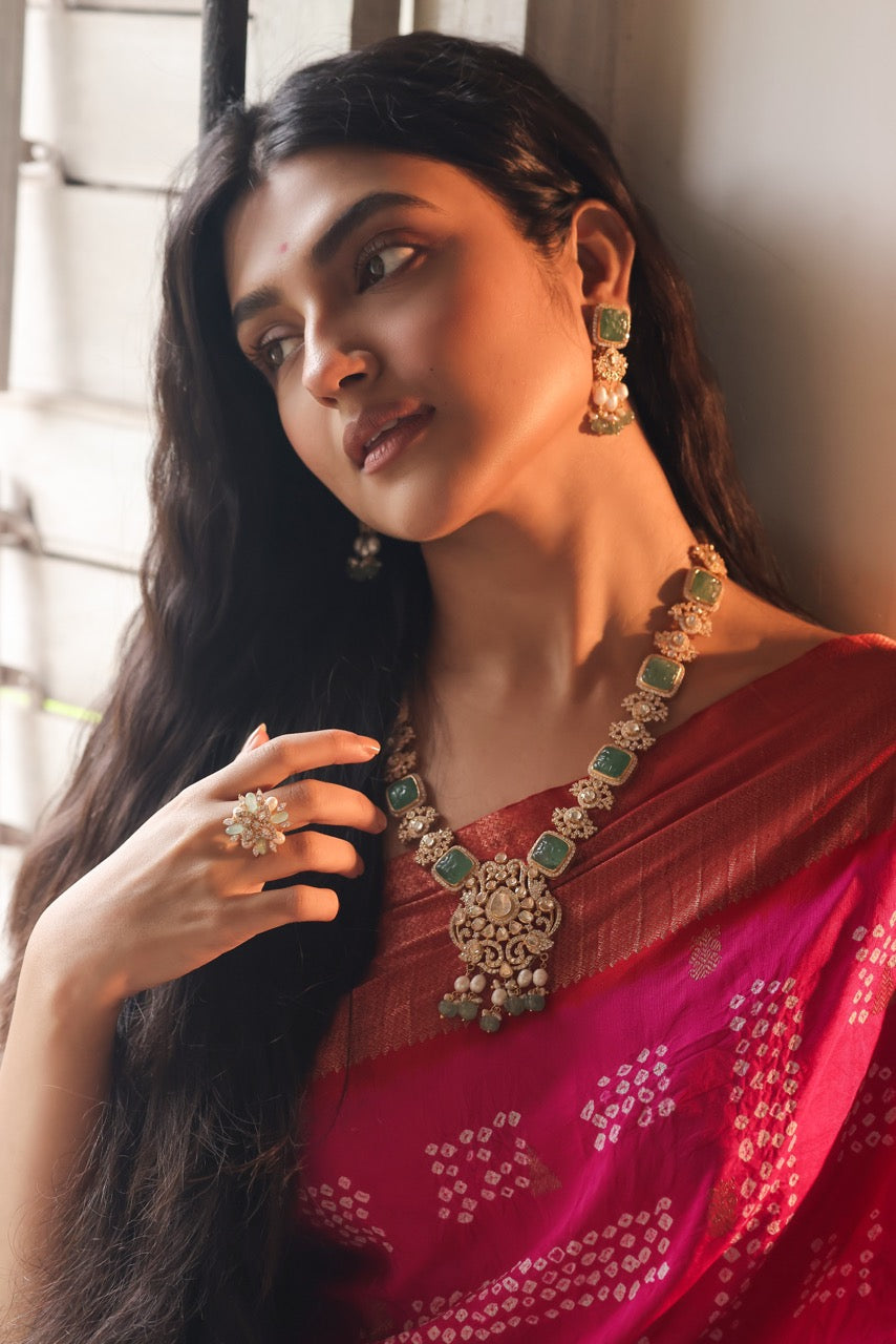 Woman wearing a red saree with jewelry, including a necklace and earrings.