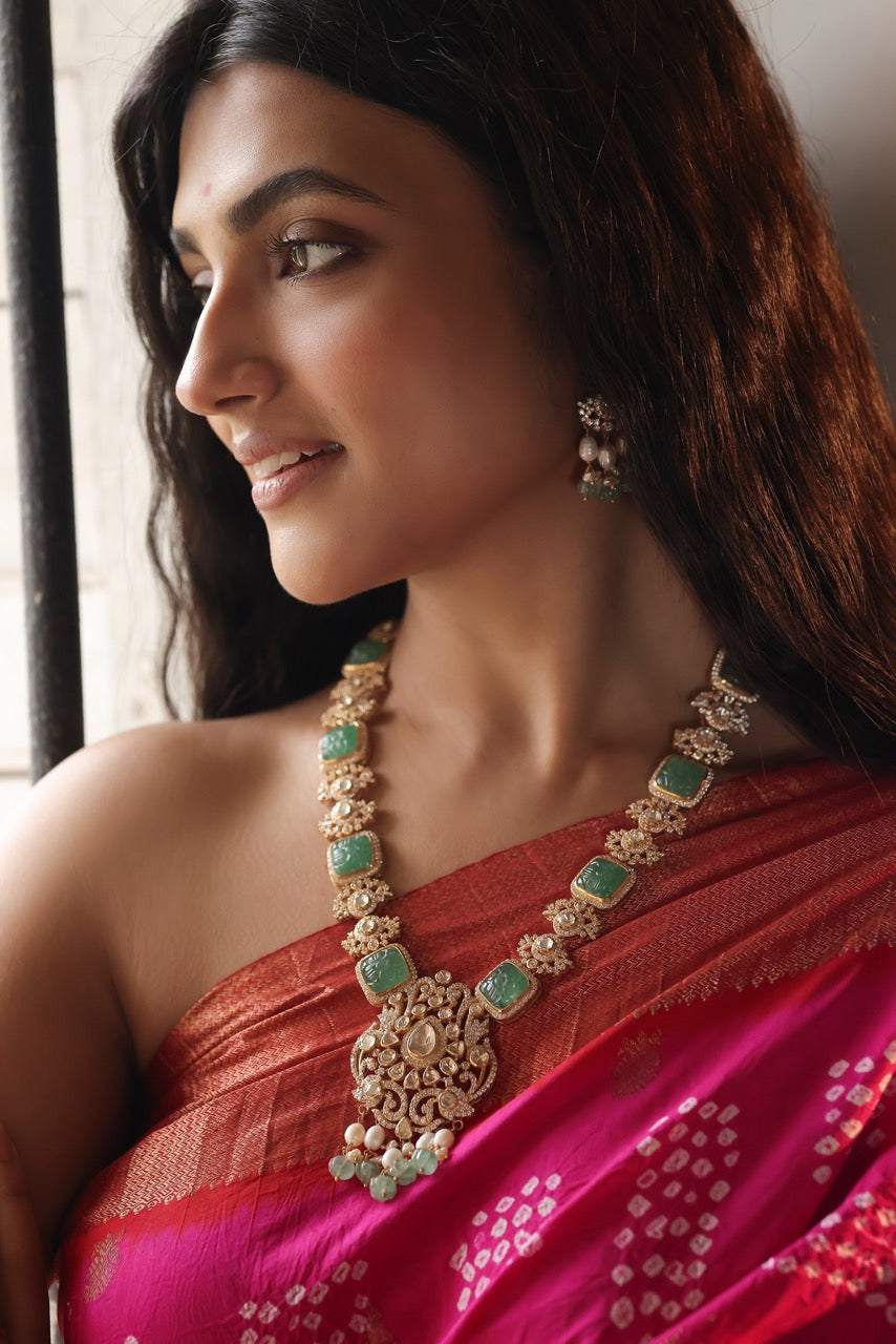 Woman wearing a red saree with golden and green jewelry