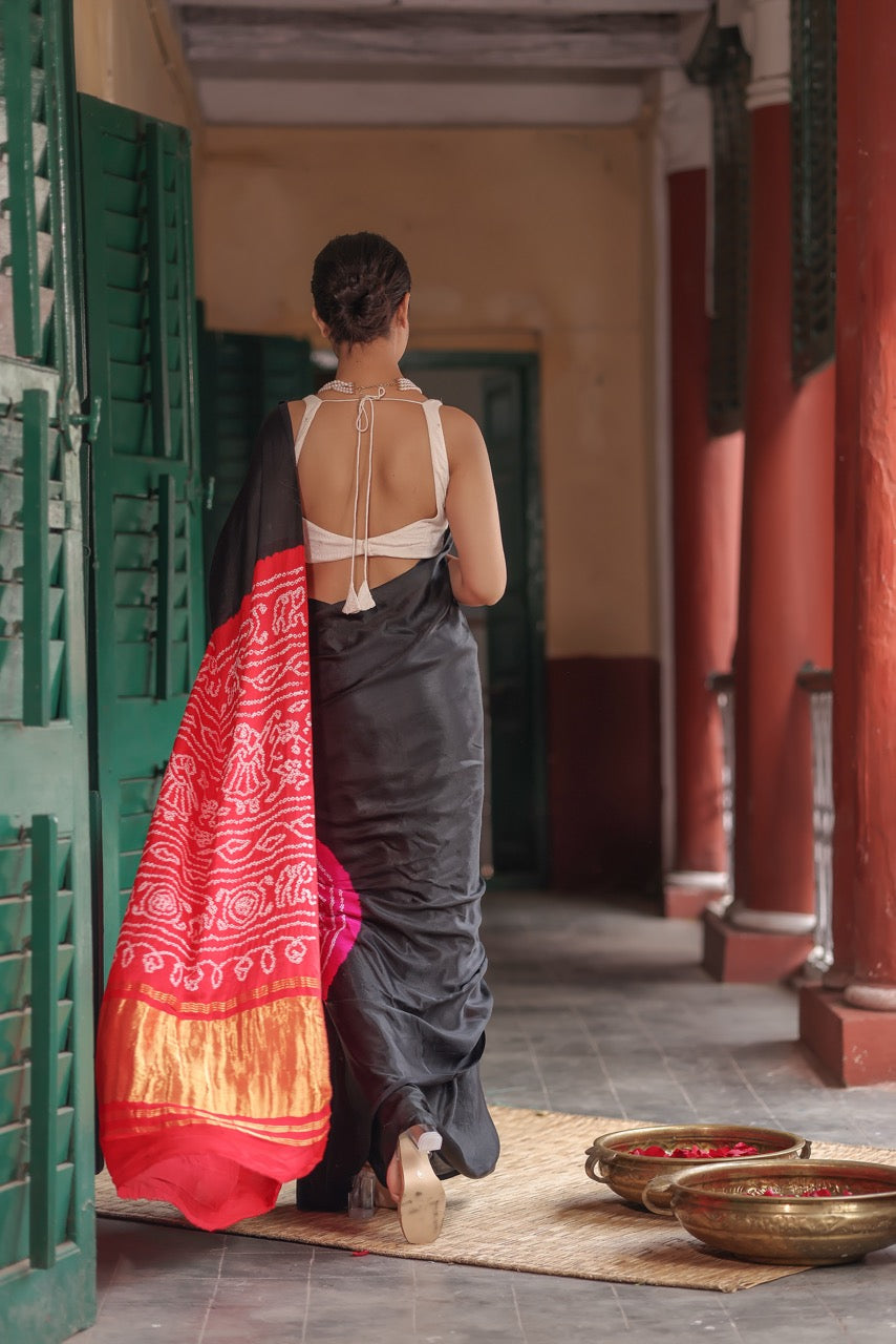 Woman in a traditional saree standing in a hallway with red and gold elements.