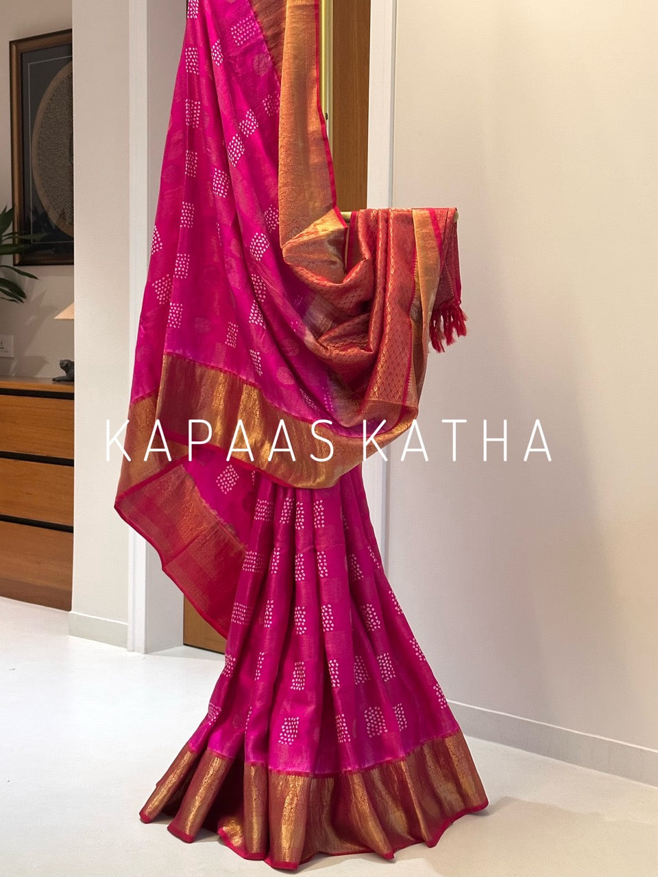 A draped pink and gold saree with woven patterns and a wide gold border.