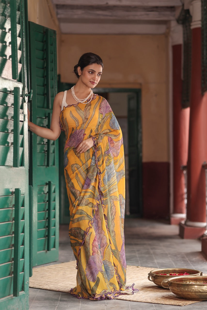 Woman in a yellow and purple saree standing in a traditional setting