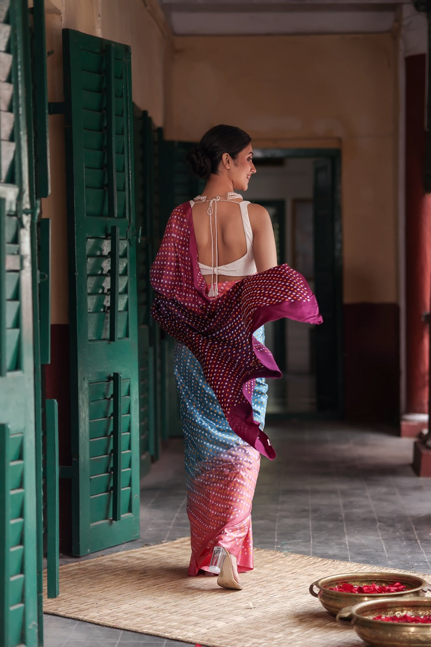 Woman wearing a colorful saree in an indoor setting with green doors and a tiled floor.