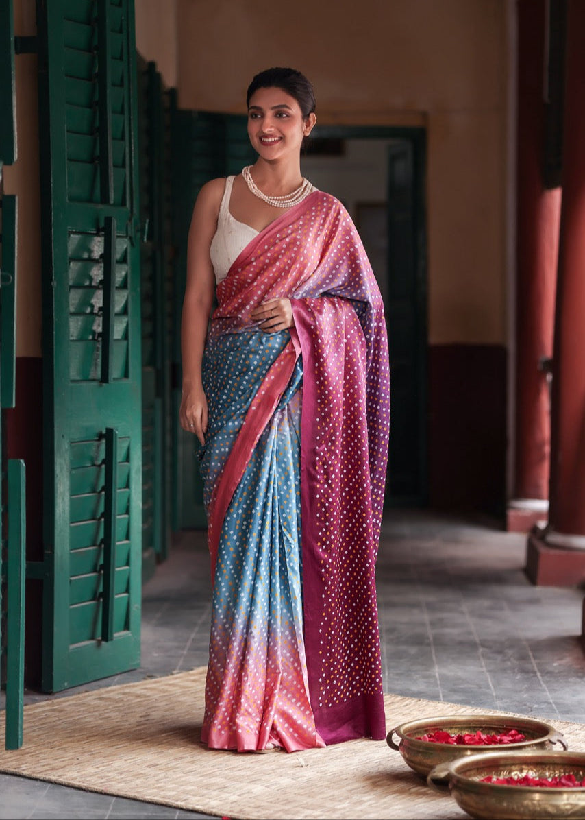 Woman wearing a colorful saree in an indoor setting with green doors and a tiled floor.