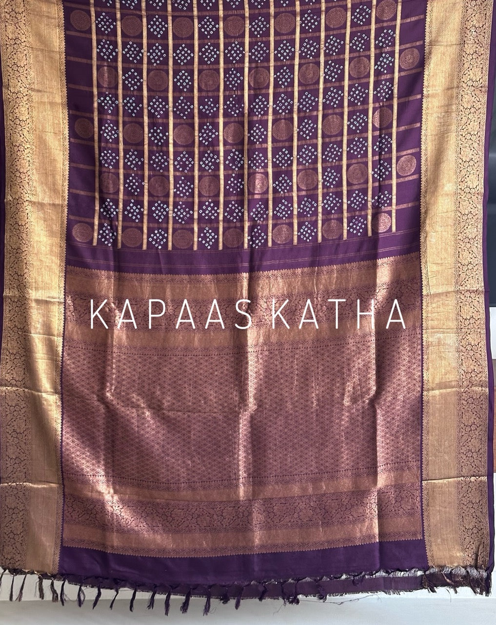Buy pure Vasundhara silk Bandhani saree in plum purple with gold zari checks & rich pallu. Authentic handwoven luxury online at Kapaas Katha.
