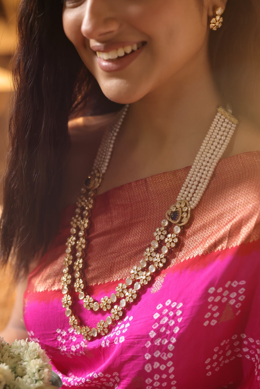 Woman in a pink saree with 92.5 silver jewelry with moissanite polki  and pearls holding flowers indoors
