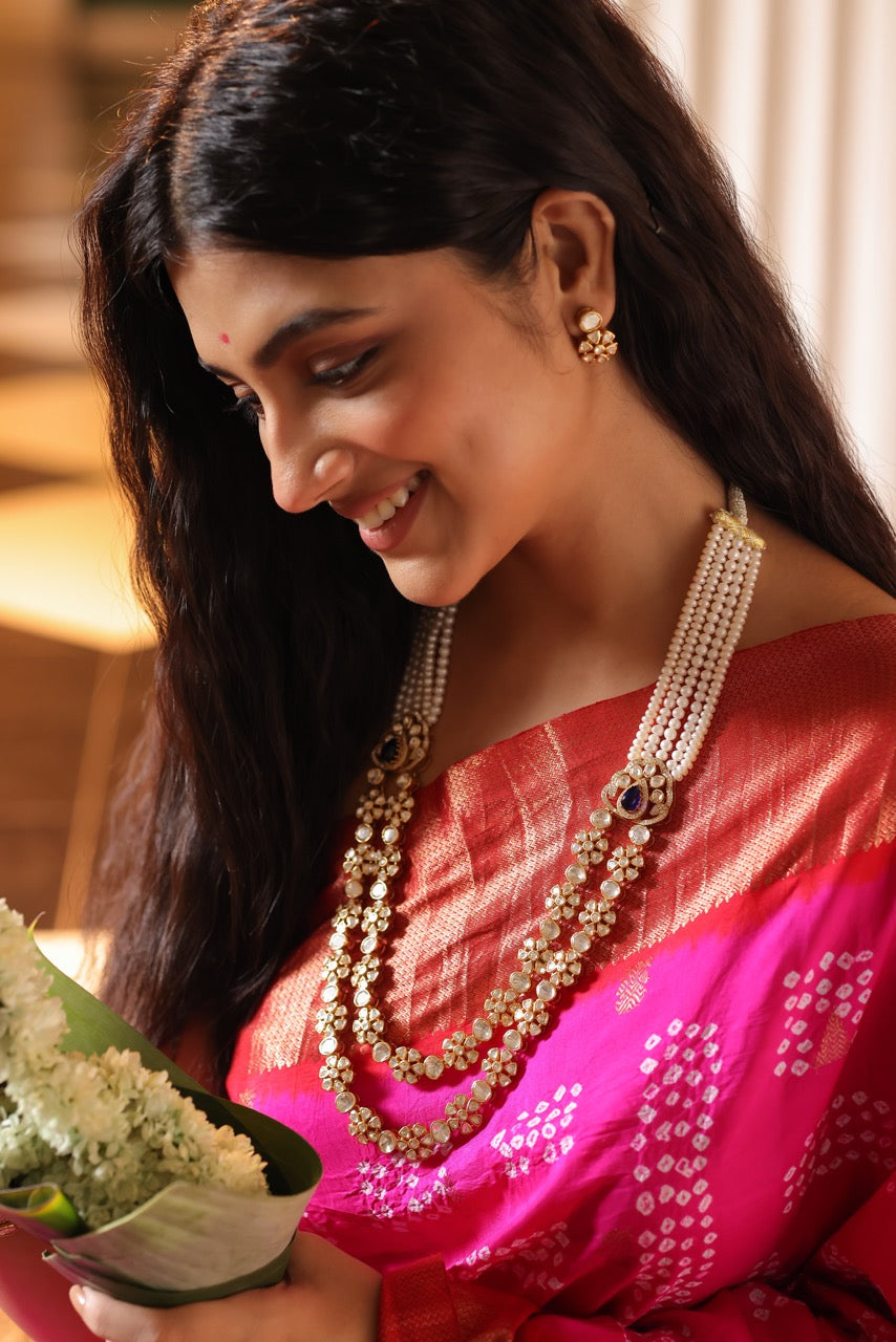 Woman in a pink saree with 92.5 silver jewelry with moissanite polki  and pearls holding flowers indoors