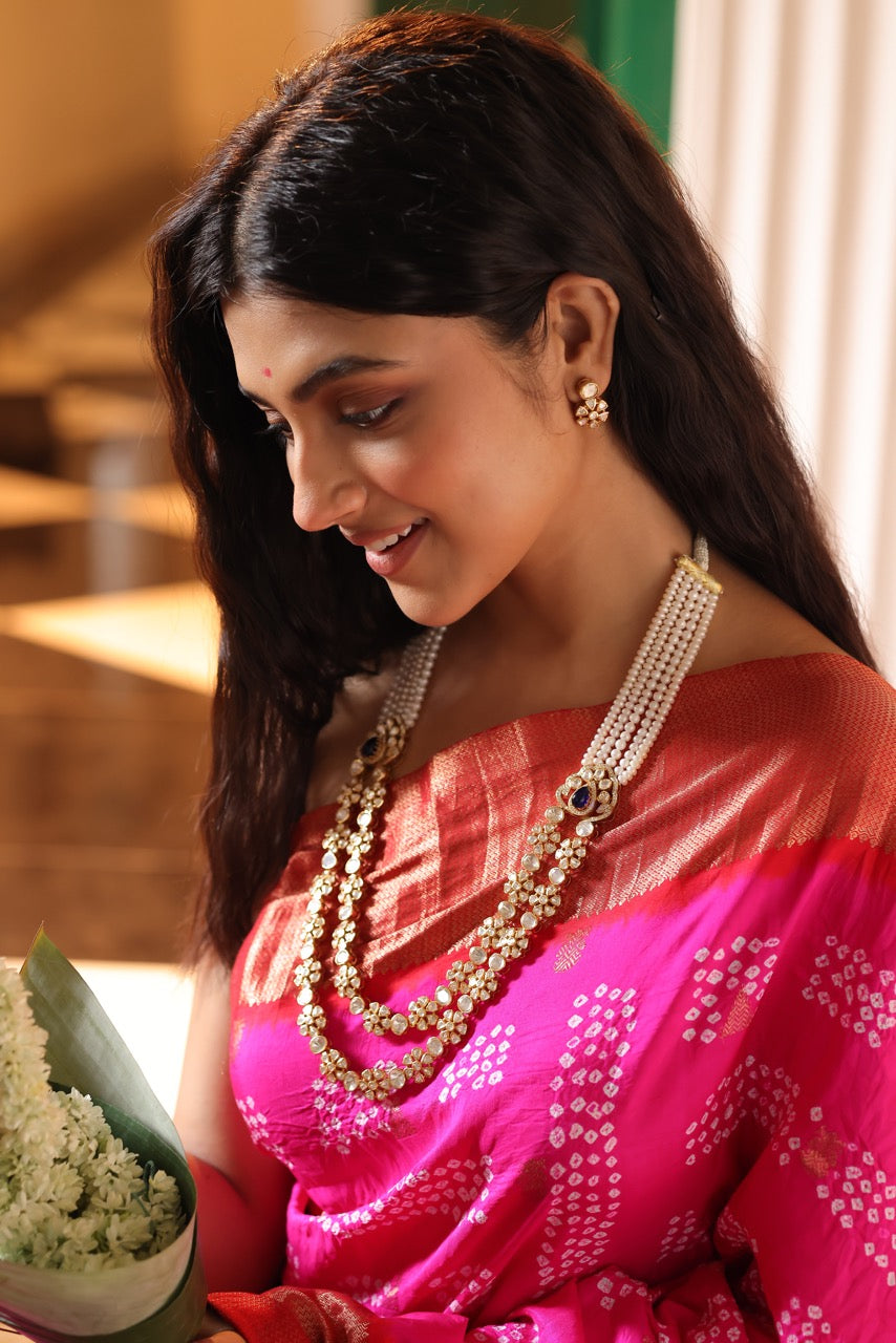 Woman in a pink saree with 92.5 silver jewelry with moissanite polki  and pearls holding flowers indoors