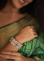 Woman wearing a green saree with a silver bracelet featuring red and green stones.