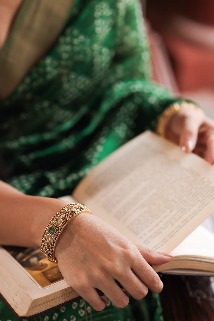 Hand wearing a 92.5 silver kada with green stones on an open book