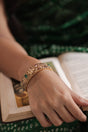 Hand wearing a 92.5 silver kada with green stones on an open book