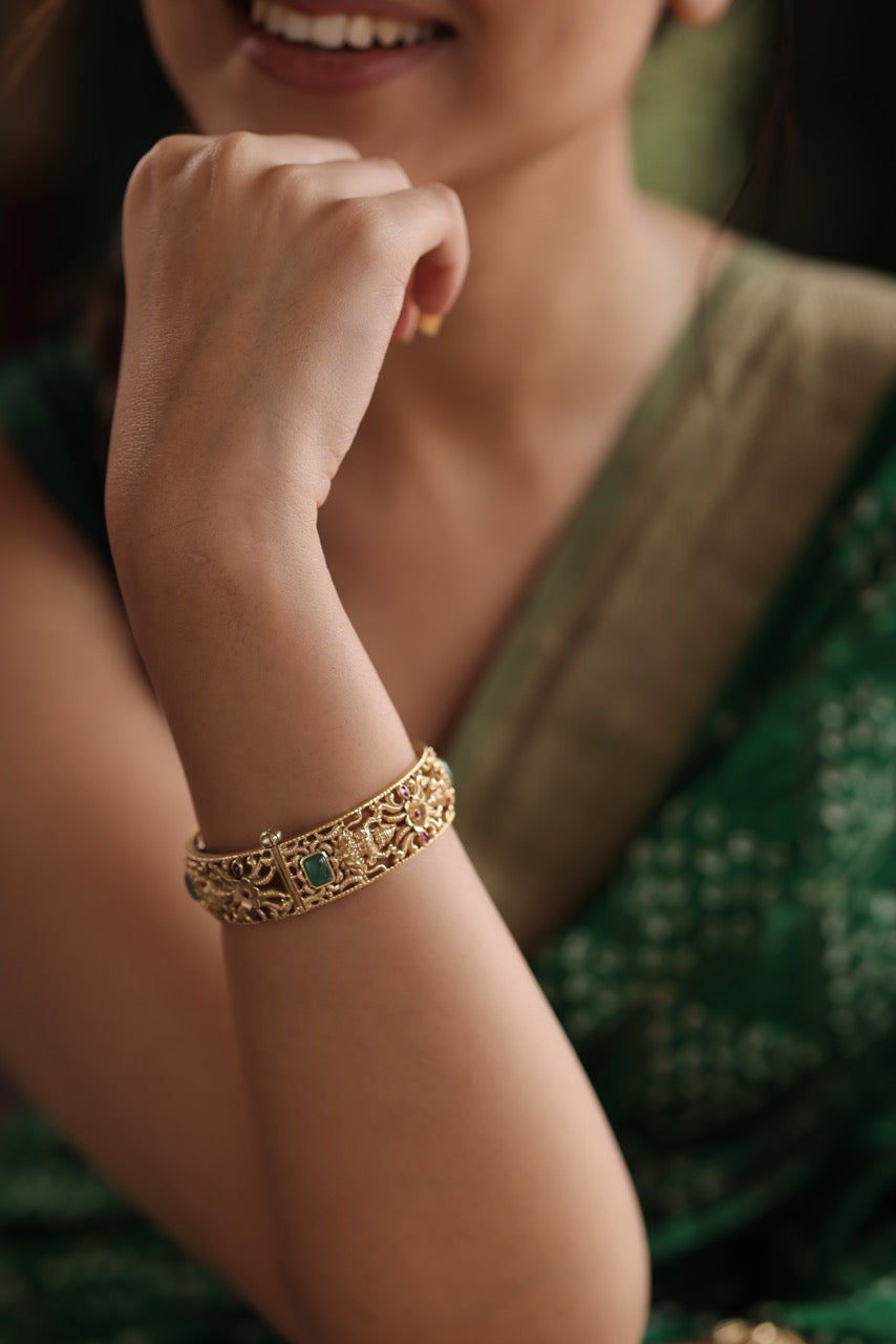 Hand wearing a 92.5 silver kada with green stones on an open book