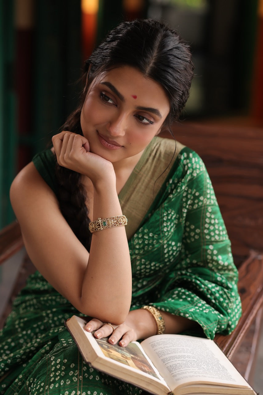 Hand wearing a 92.5 silver kada with green stones on an open book