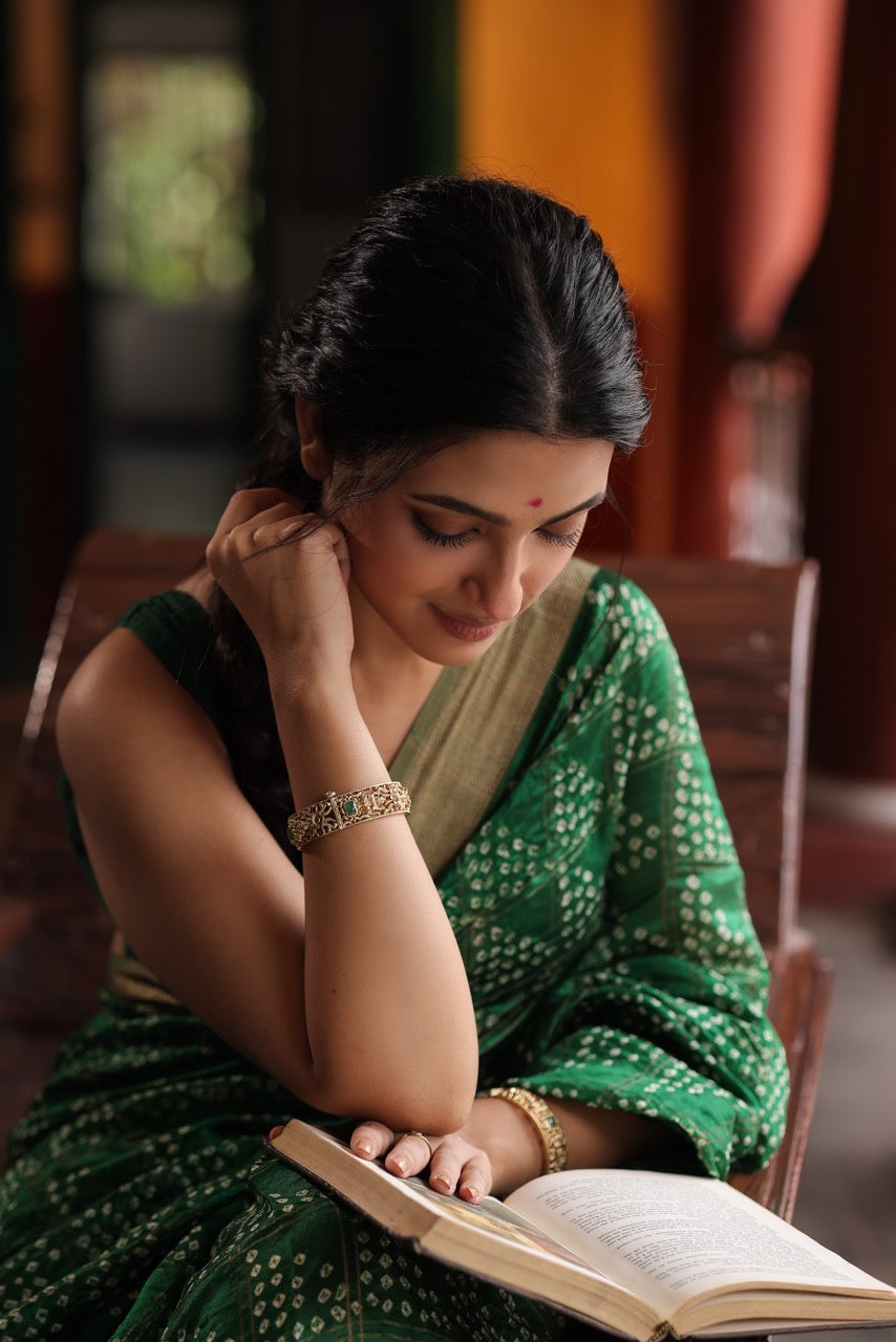 Hand wearing a 92.5 silver kada with green stones on an open book