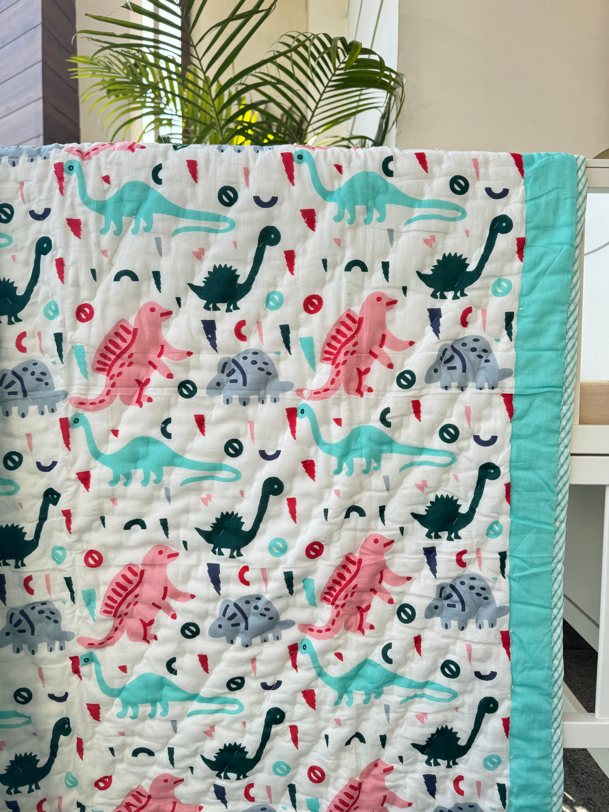 vibrant turquoise dinosaur themed baby quilt made in India ideal for toddler gifts in UK and Canada