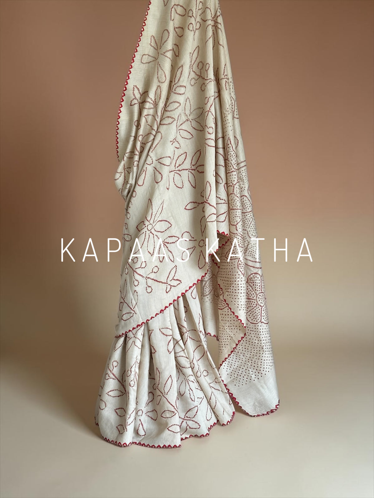 Buy pure Munga silk Bandhani saree in linen beige with soft red ghangura border. Lightweight handloom elegance for daytime festivities at Kapaas Katha.