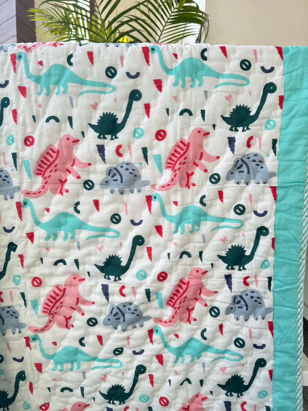 premium cotton baby quilt with dino theme in turquoise and rainbow accents for resellers in UAE and Australia