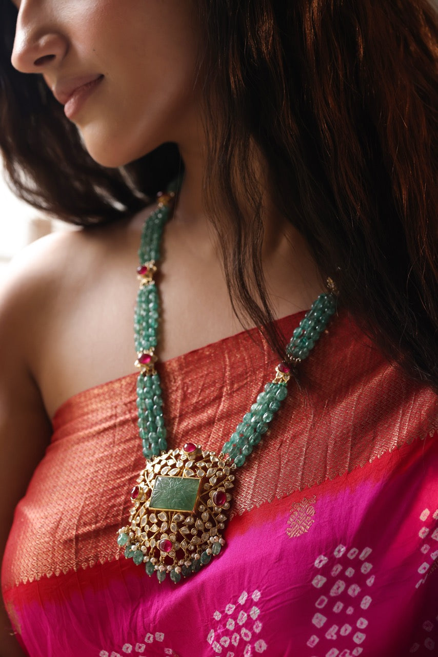 Woman wearing a traditional necklace with a pink saree