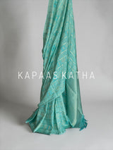 Shop pure Vasundhara silk Bandhani saree in sea green with gold zari checks & rich tissue pallu. Authentic handwoven luxury online at Kapaas Katha.