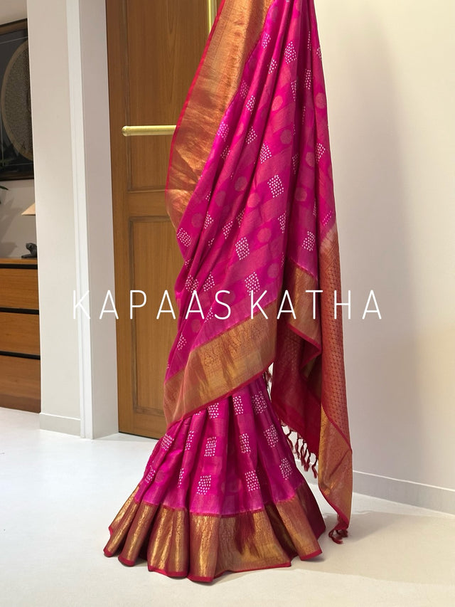 A draped pink and gold Banarasi silk saree with intricate zari work.