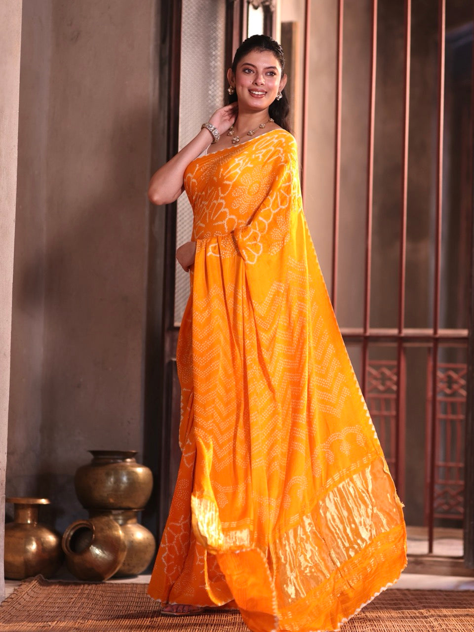 Woman wearing an orange saree with a traditional setting