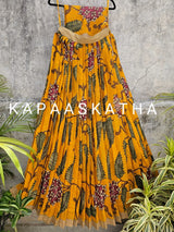 Yellow floral dress on a hanger with 'Kapaaskatha' branding against a gray textured wall.