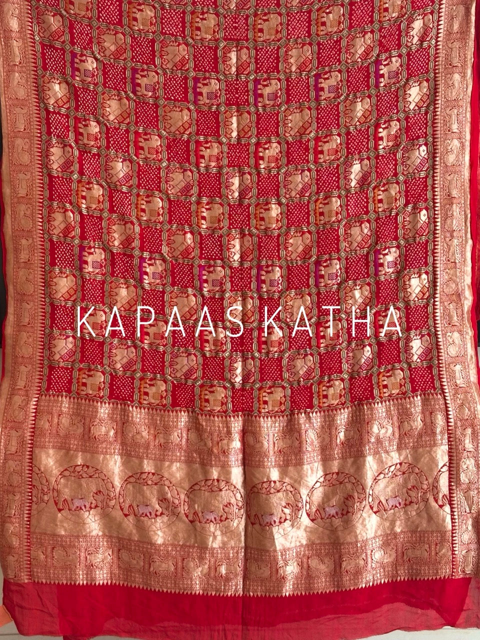 Buy pure Banarasi georgette Bandhani saree in vermilion red with gold zari elephant motifs & rich woven pallu. Authentic handloom luxury online at Kapaas Katha.