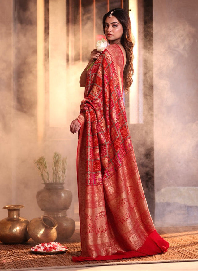 Buy pure Banarasi georgette Bandhani saree in vermilion red with gold zari elephant motifs & rich woven pallu. Authentic handloom luxury online at Kapaas Katha.