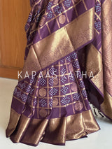 Buy pure Vasundhara silk Bandhani saree in plum purple with gold zari checks & rich pallu. Authentic handwoven luxury online at Kapaas Katha.