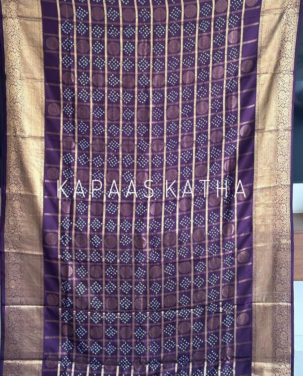 Buy pure Vasundhara silk Bandhani saree in plum purple with gold zari checks & rich pallu. Authentic handwoven luxury online at Kapaas Katha.