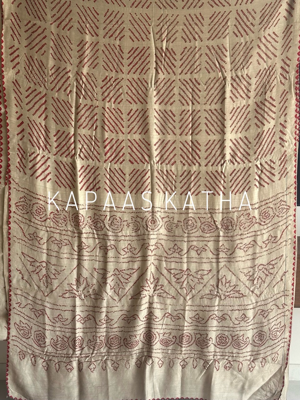 Buy pure Munga silk Bandhani saree in linen beige with soft red ghangura border. Lightweight handloom elegance for daytime festivities at Kapaas Katha.
