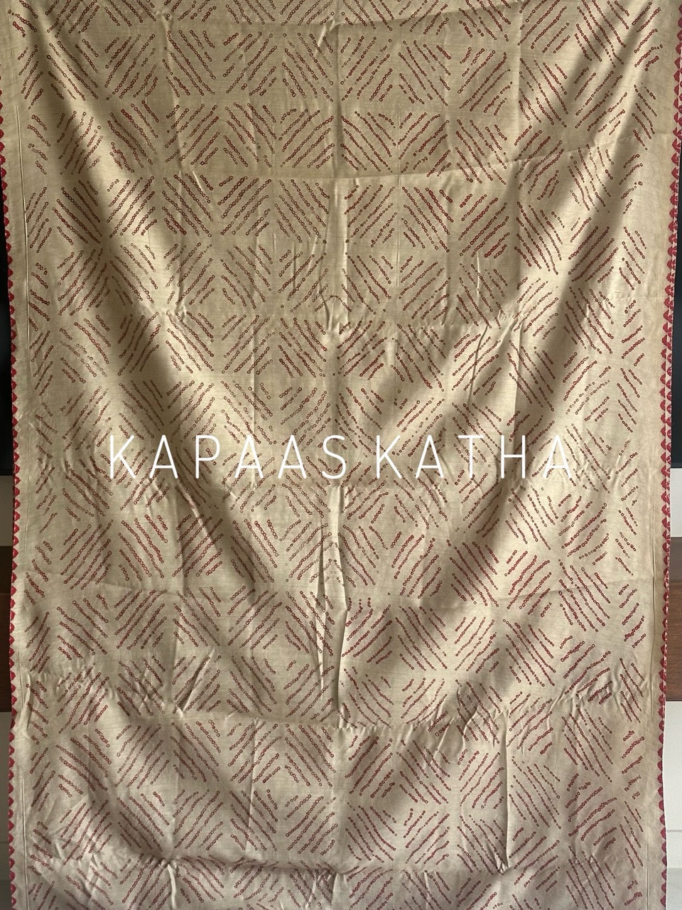 Buy pure Munga silk Bandhani saree in linen beige with soft red ghangura border. Lightweight handloom elegance for daytime festivities at Kapaas Katha.