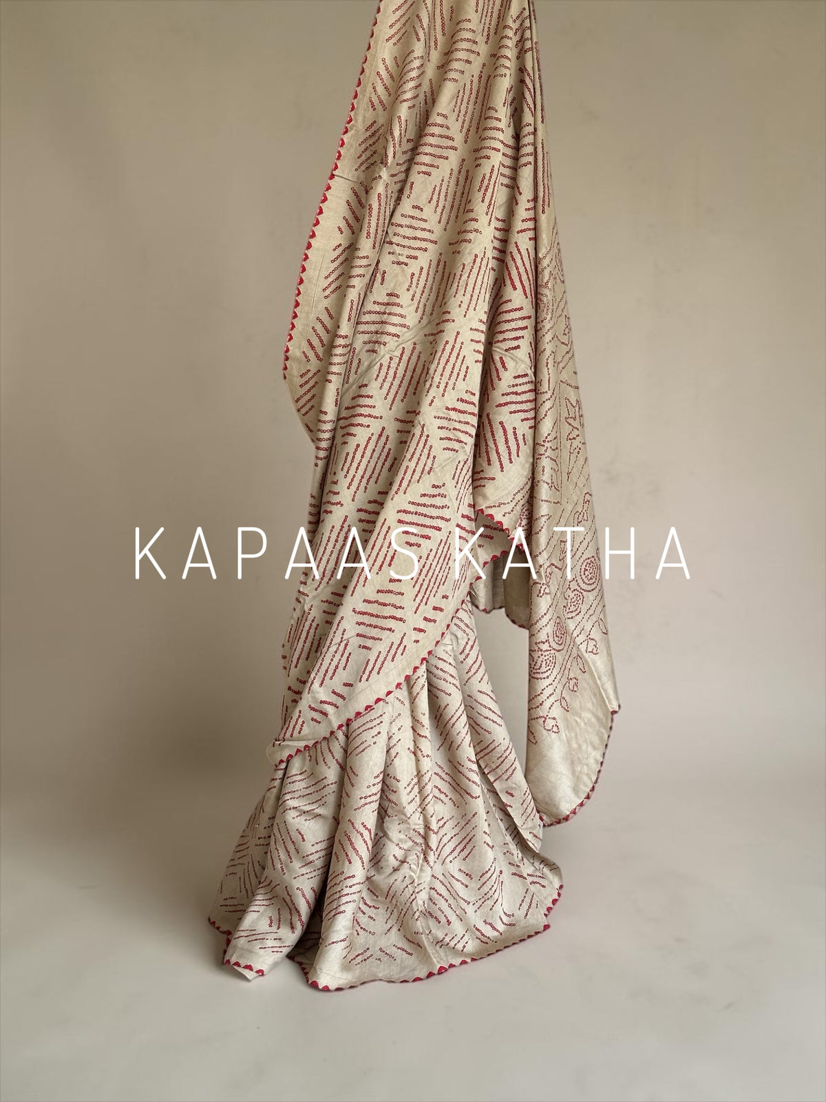 Buy pure Munga silk Bandhani saree in linen beige with soft red ghangura border. Lightweight handloom elegance for daytime festivities at Kapaas Katha.