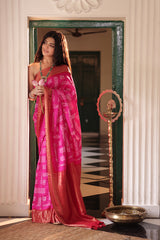 Woman in a pink and red saree standing in front of a mirror.