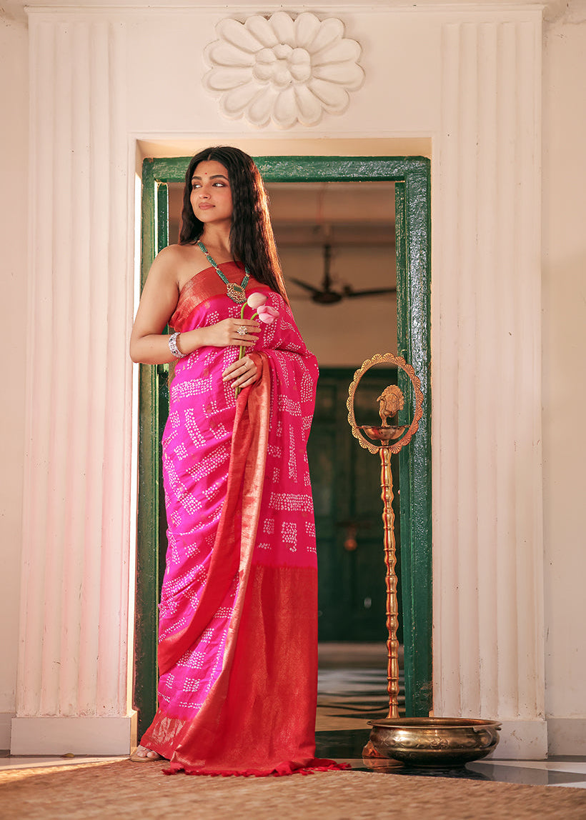 Woman in a pink saree standing in front of a mirror with decorative elements.