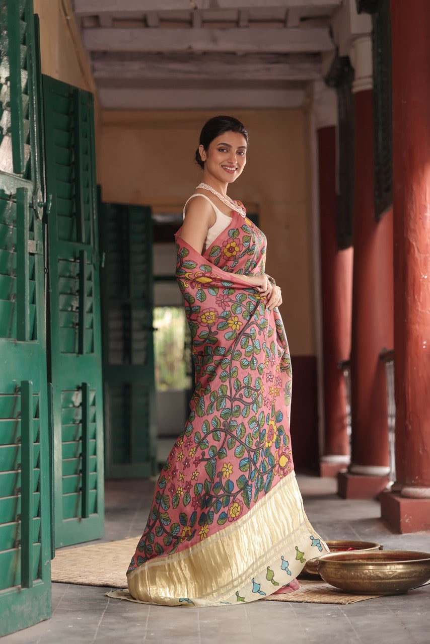 Woman in a traditional saree standing in an outdoor setting with architectural elements.