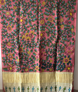 Woman in a floral saree standing in an indoor setting with traditional decor.